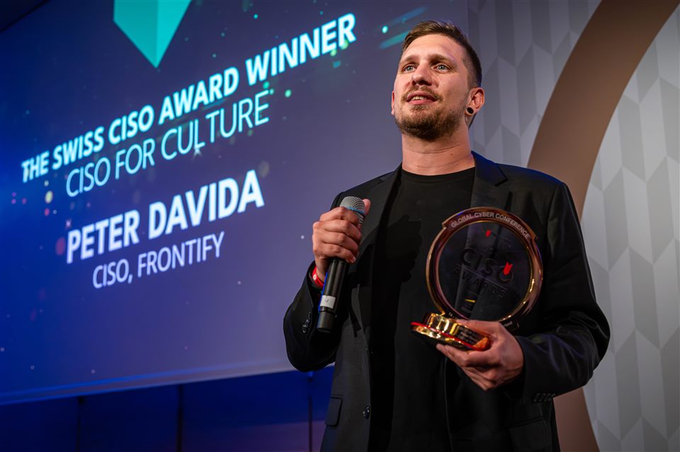Peter on stage holding the Swiss CISO Award trophy, with a screen behind him reading “The Swiss CISO Award Winner: CISO for Culture, Peter Davida, CISO, Frontify”.