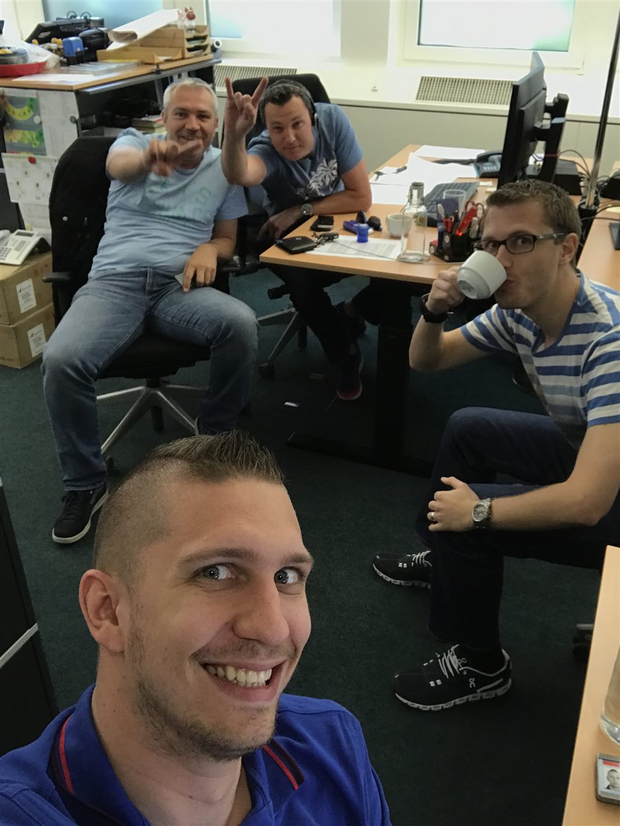 Office selfie of Peter with three colleagues mucking about at their desks.